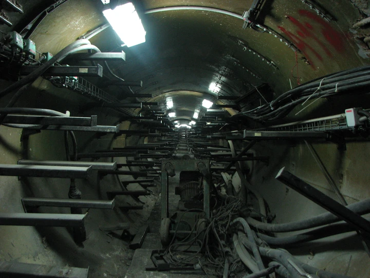 Cables and fluorescent lights receding through an industrial tunnel