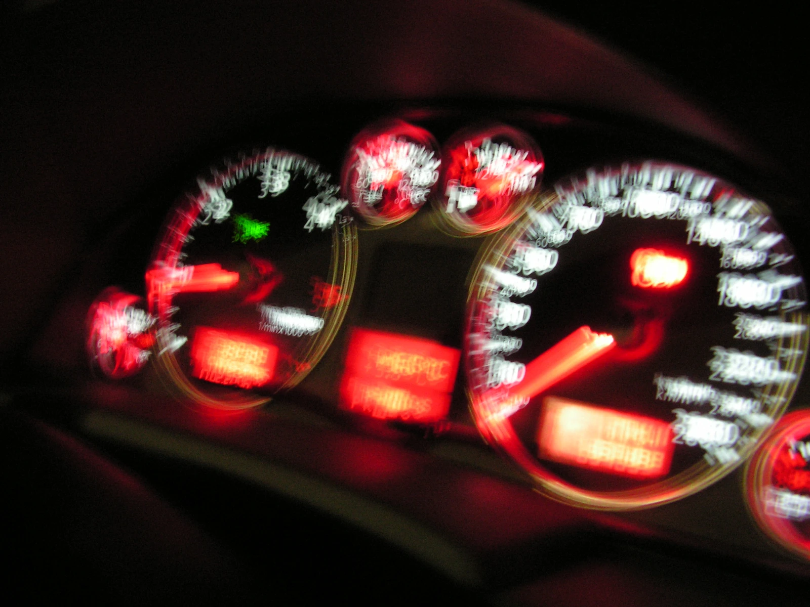 A car instrument panel blurred into red and white trails of light