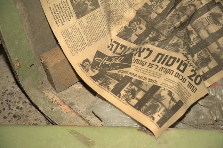 An old Hebrew newspaper lying among dusty equipment